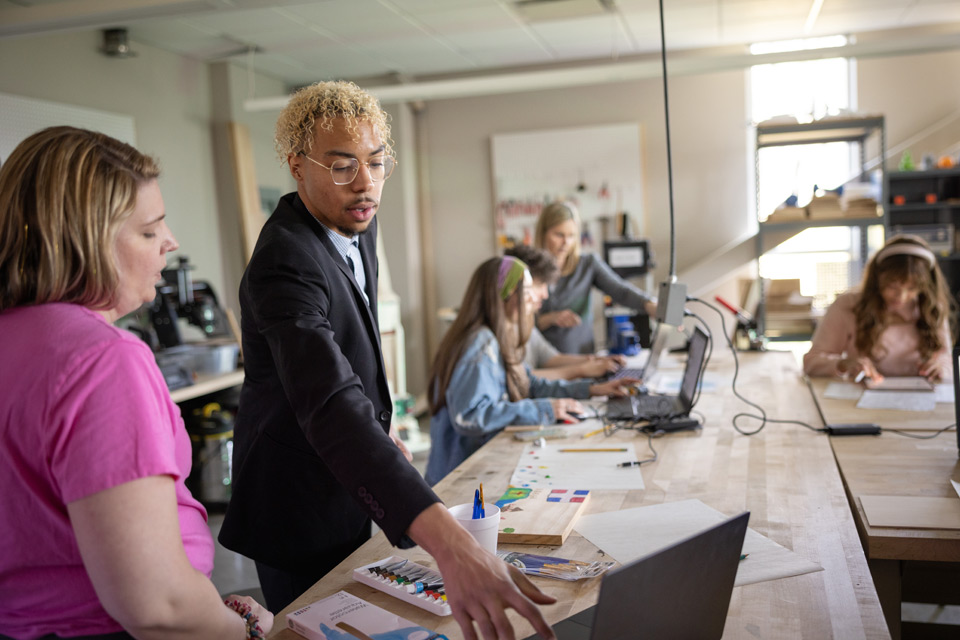 student in makerspace with other students