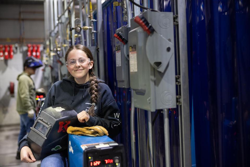 female welder sitting next to equipment