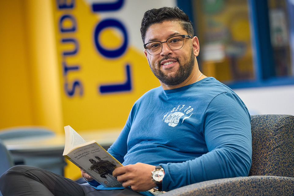 Adult male student sitting in a chair reading a book
