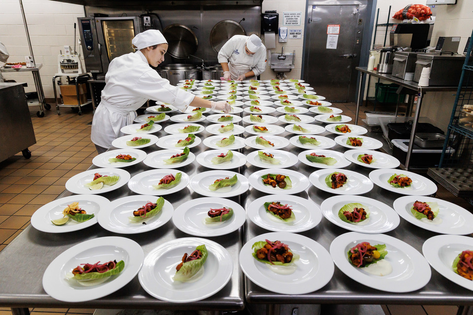 Culinary students plating dishes in a commercial kitchen