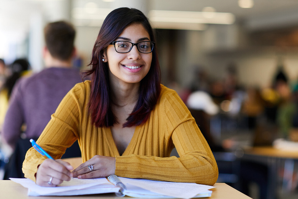 photo of student sitting at desk and smiling