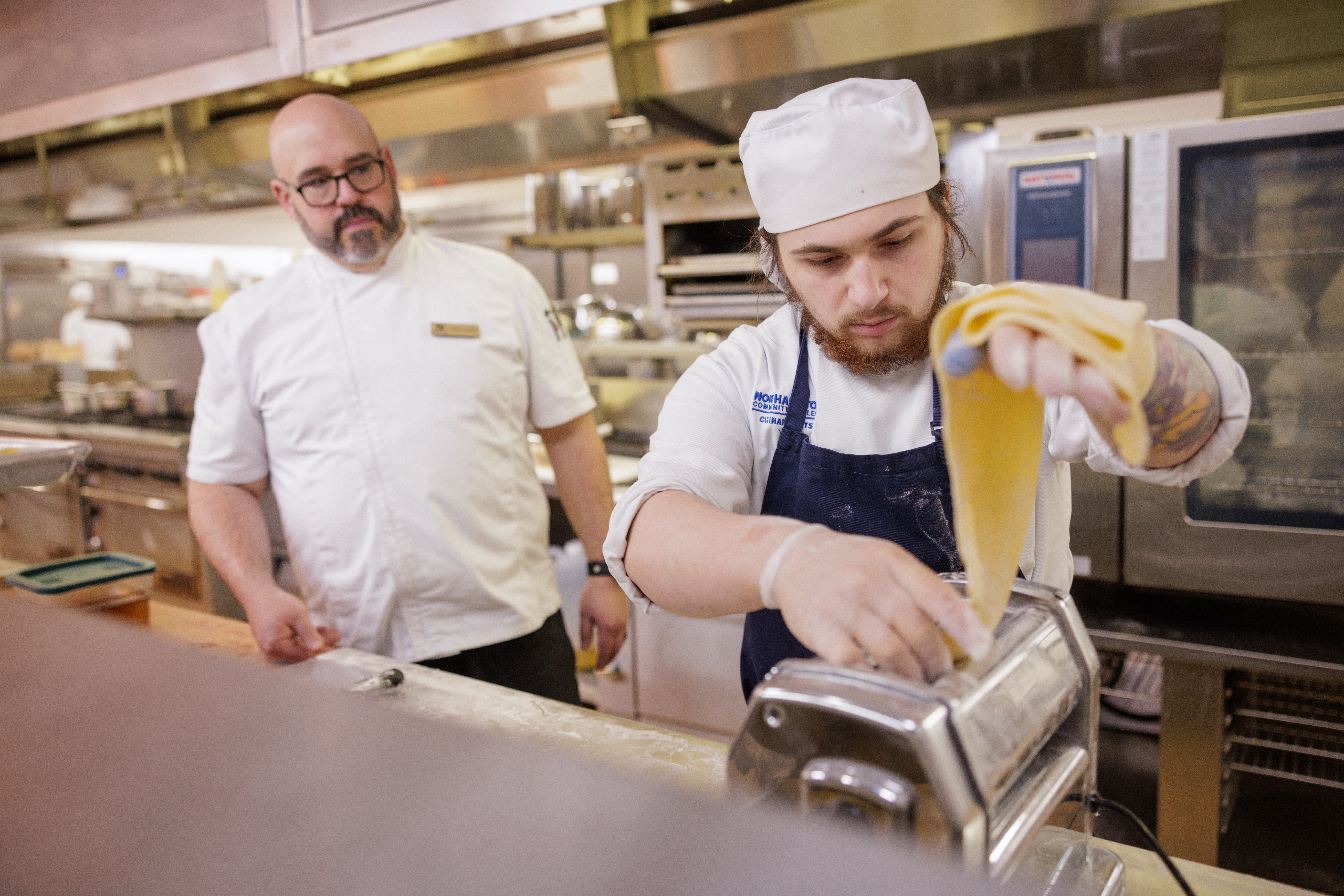 Chef Dom (left) observing a student's technique in the NCC kitchen
